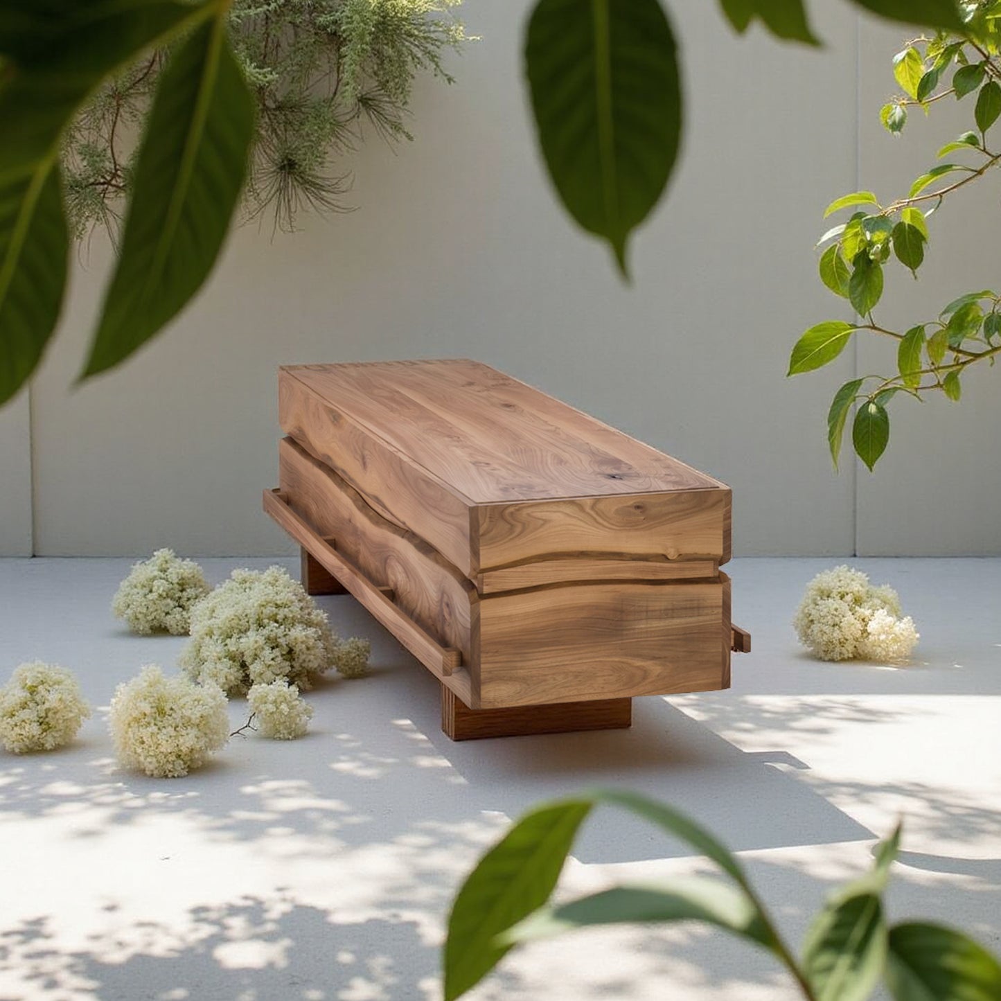 Massief iepenhouten uitvaartkist met zichtbare houtnerf, geplaatst in een serene, groene binnenplaats met schaduw en witte bloemen