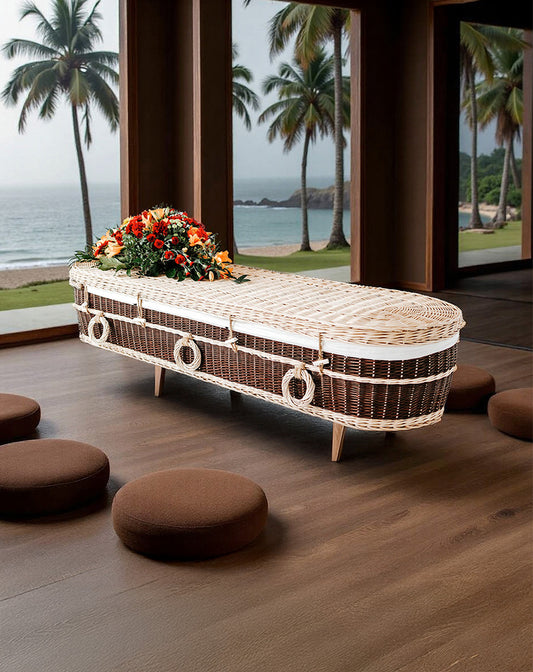 Handgevlochten wilgenteen uitvaartmand Ocean’s Embrace met ringgrepen, in een tropische, zen-achtige setting met palmen.